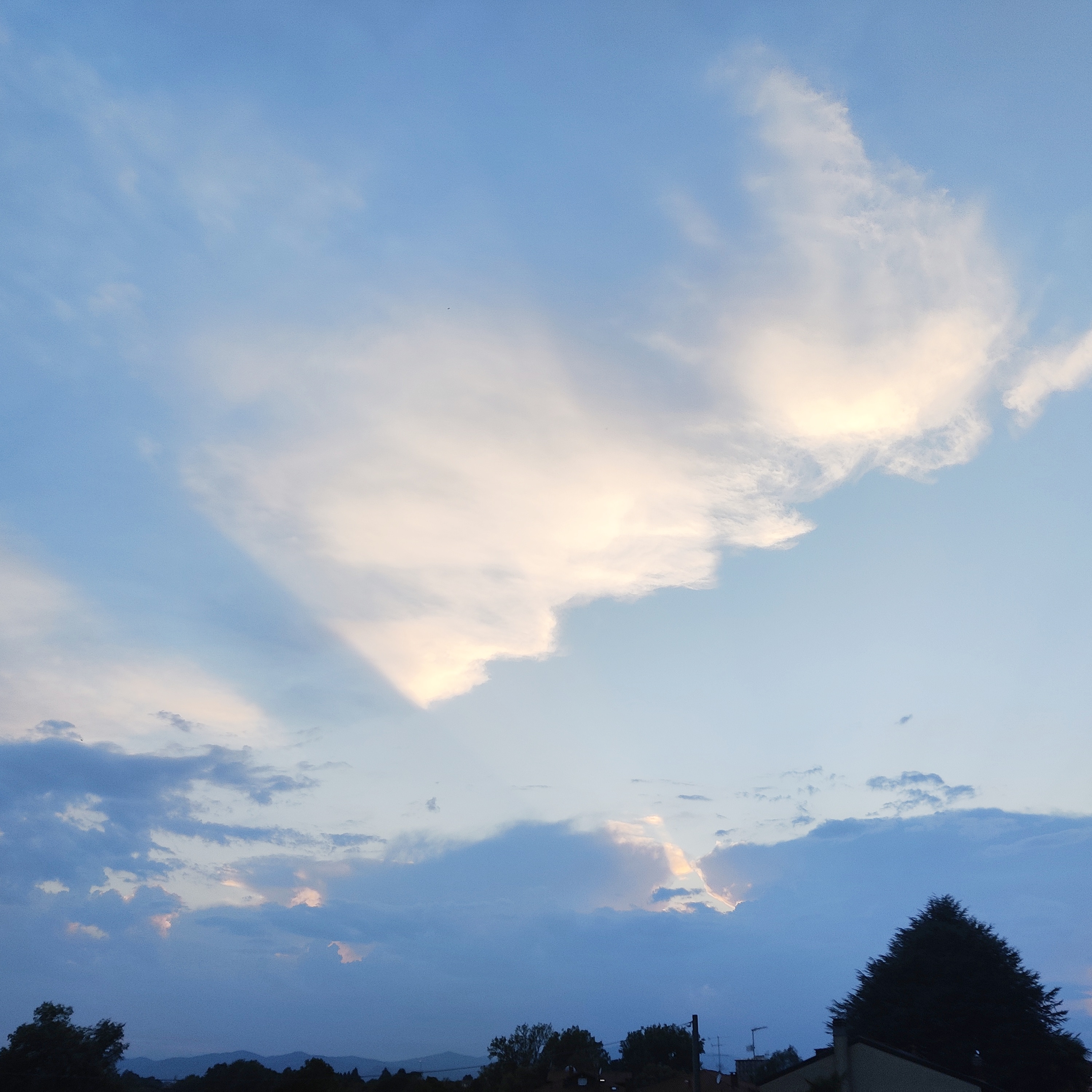 photo of a cloudy sky during a blue sunset, the clouds being lit from behind by the sun